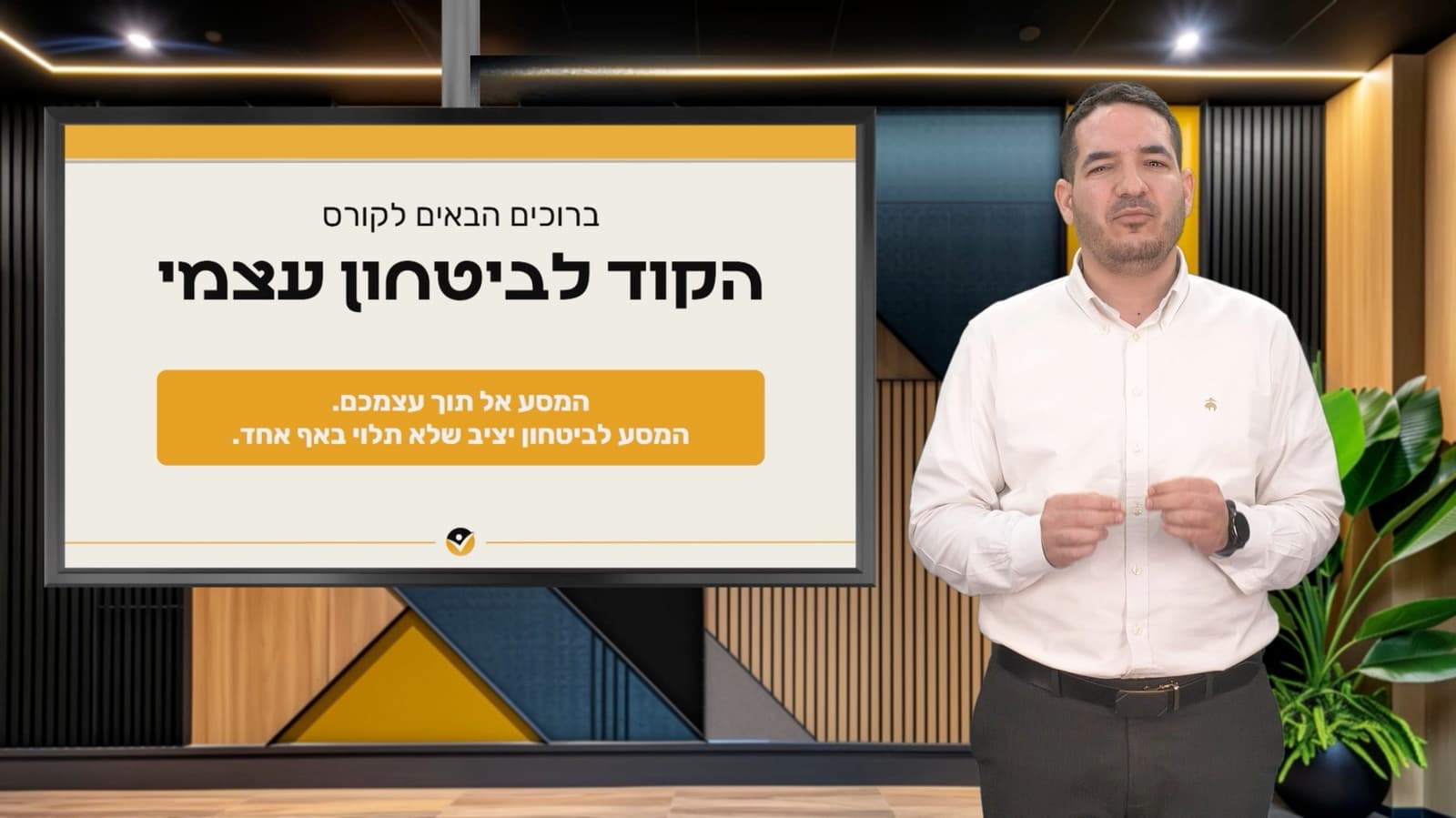 יוסף בן שושן באולפן הקורס, ליד שקופית הפתיחה ״ברוכים הבאים לקורס הקוד לביטחון עצמי״