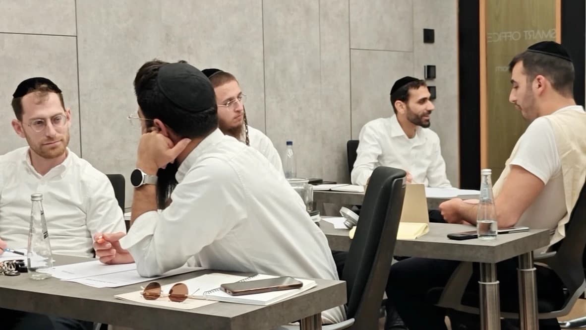 משתתפי ההכשרה מתרגלים בזוגות: אחד שואל ואחד מקשיב, סביב השולחנות בכיתה